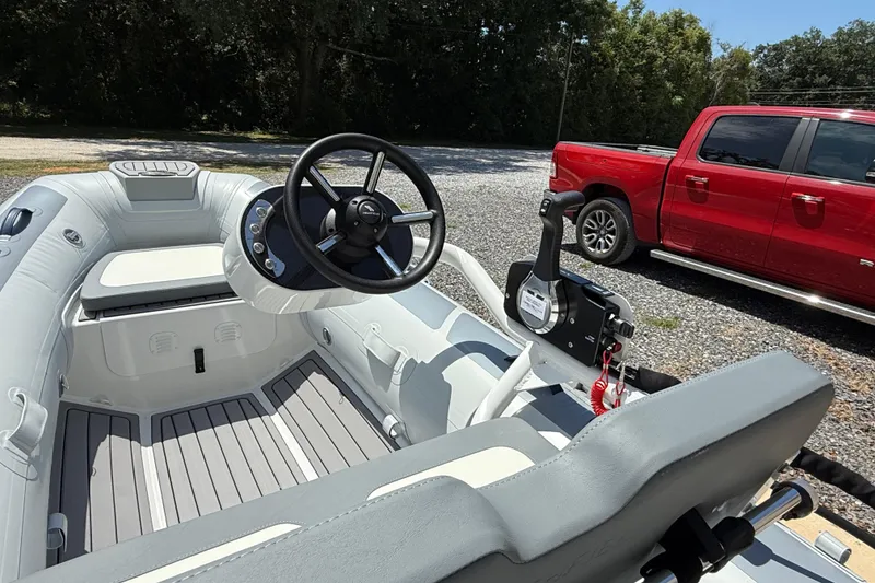 Slide: The Image of 2026 Highfield Classic 360 FCT boat interior with steering wheel, parked beside a red truck. - 9