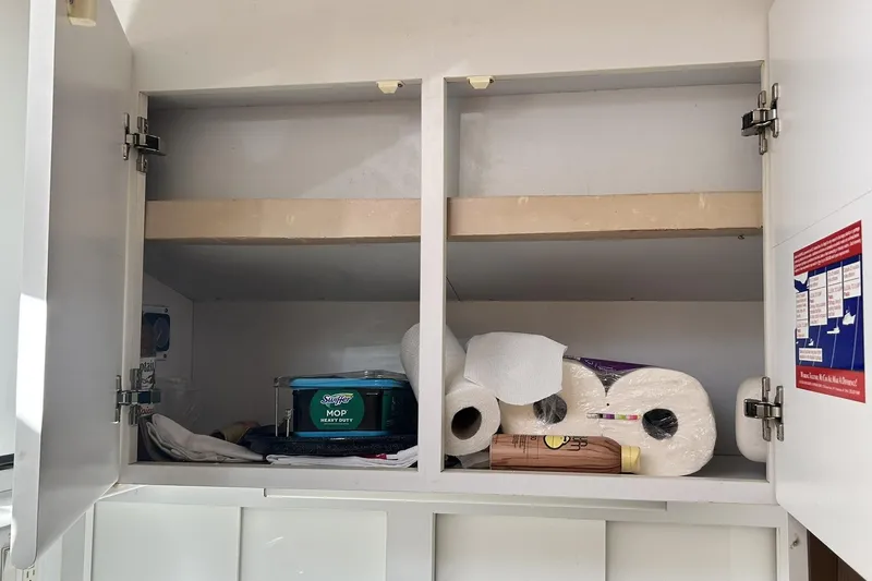 Slide: The Image of Open cabinet with cleaning supplies and paper towels on a Hatteras 39 Sport Express, 1996 model. - 32