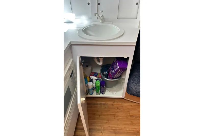 Slide: The Image of Cabinet under sink in 1996 Hatteras 39 Sport Express, storing cleaning supplies. - 34