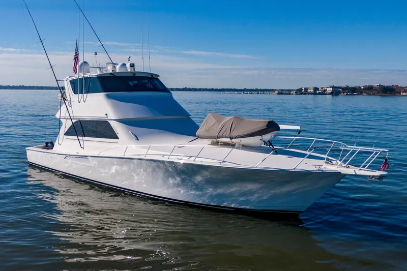Slide: The Image of 2002 Viking 65 Enclosed Bridge yacht on calm water, clear sky background. - 2