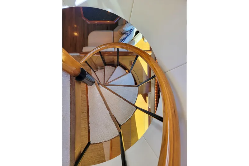 Slide: The Image of Spiral staircase inside 2002 Viking 65 Enclosed Bridge yacht, featuring elegant wood and carpet design. - 50