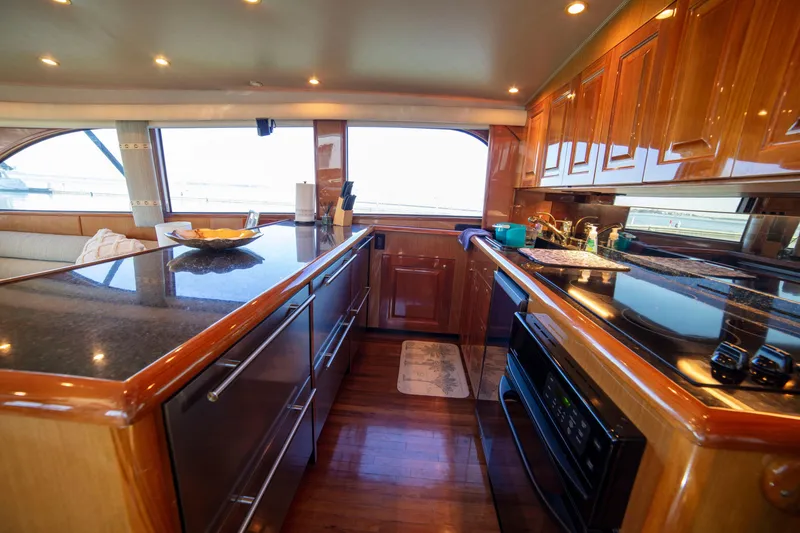 Slide: The Image of Luxurious kitchen interior of 2002 Viking 65 Enclosed Bridge yacht with wood cabinetry and modern appliances. - 61