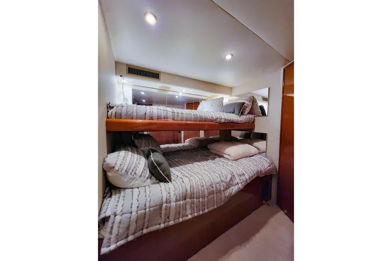 Slide: The Image of Bunk beds in 2002 Viking 65 Enclosed Bridge yacht cabin, featuring cozy bedding and ambient lighting. - 81