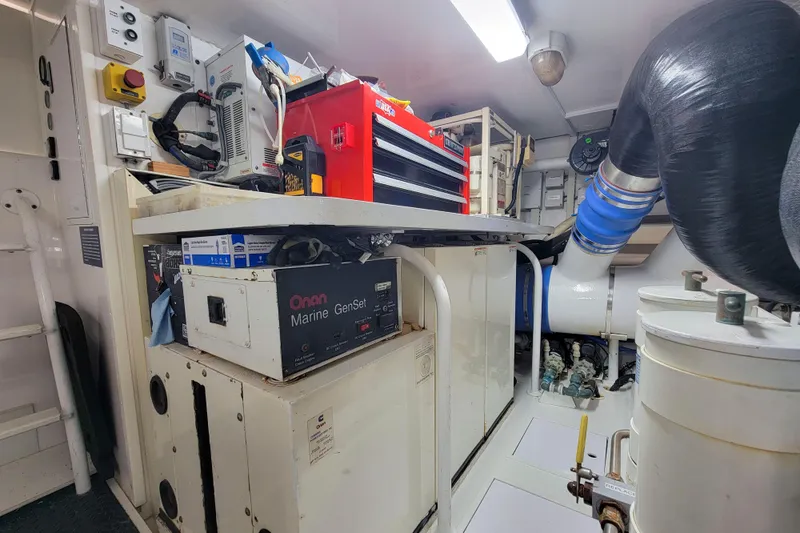 Slide: The Image of Engine room of 2002 Viking 65 Enclosed Bridge with Onan Marine GenSet and tool storage. - 89