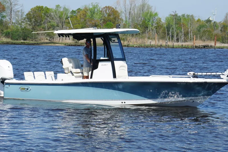 The Image of 2023 Sea Hunt BX 25 FS boat cruising on a calm lake with lush greenery. - 0