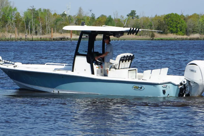 Slide: The Image of 2023 Sea Hunt BX 25 FS boat cruising on a calm river with lush greenery. - 10