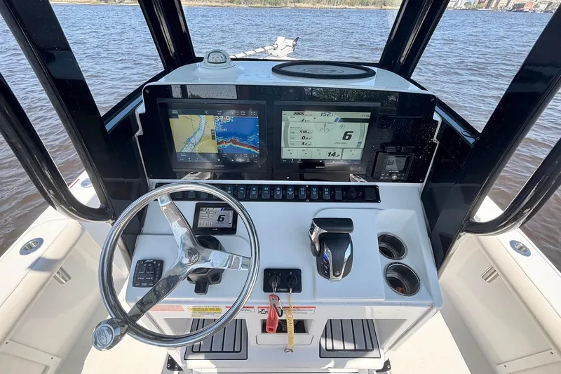 Slide: The Image of 2023 Sea Hunt BX 25 FS boat dashboard with navigation screens and steering wheel. - 13