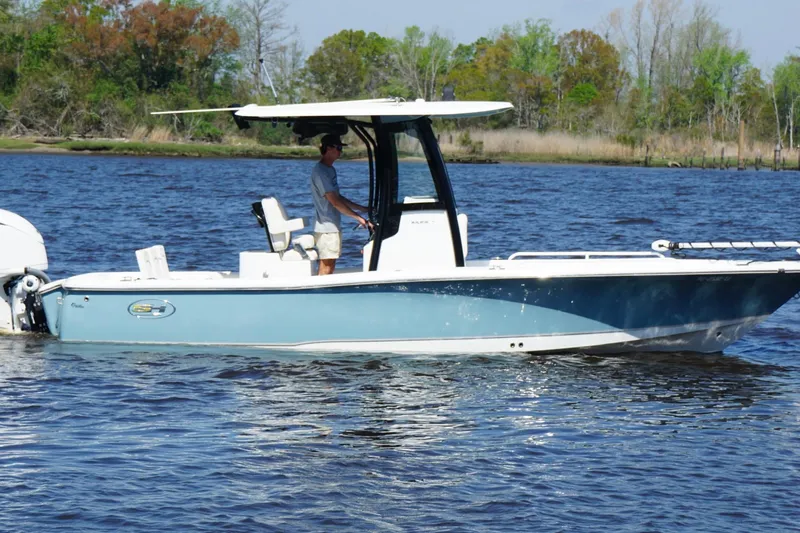 Slide: The Image of 2023 Sea Hunt BX 25 FS boat cruising on a calm river with lush greenery. - 2