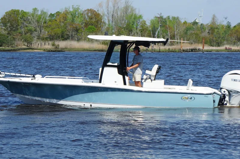 Slide: The Image of 2023 Sea Hunt BX 25 FS boat cruising on a calm river with lush greenery. - 3