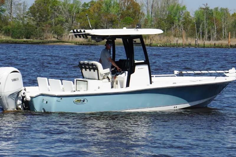 Slide: The Image of 2023 Sea Hunt BX 25 FS boat cruising on a calm river with lush greenery. - 5