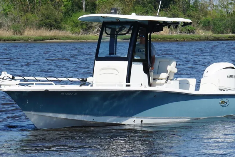 Slide: The Image of 2023 Sea Hunt BX 25 FS boat cruising on a calm river with lush greenery. - 6