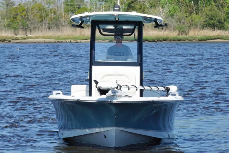 Slide: The Image of 2023 Sea Hunt BX 25 FS boat on water, front view, with lush shoreline background. - 7