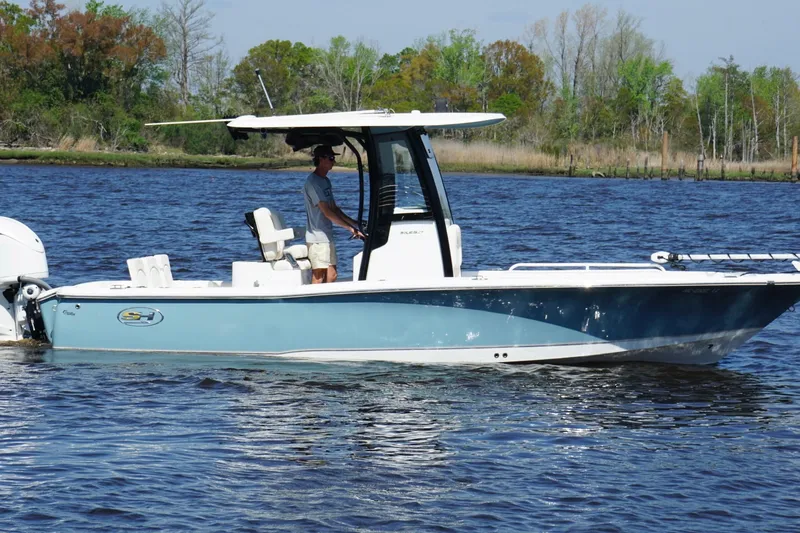 Slide: The Image of 2023 Sea Hunt BX 25 FS boat cruising on a calm river with lush greenery. - 9