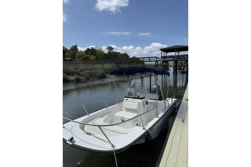 The Image of 2016 Boston Whaler 170 Montauk boat docked by a scenic riverside under a clear sky. - 0