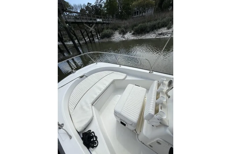 Slide: The Image of 2016 Boston Whaler 170 Montauk boat interior with seating and rod holders by a dock. - 12
