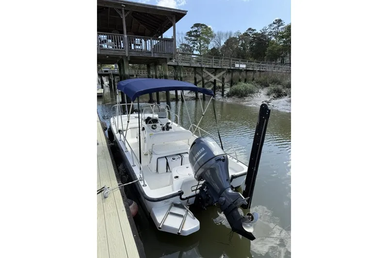Slide: The Image of 2016 Boston Whaler 170 Montauk boat docked with Yamaha outboard motor and blue canopy. - 22