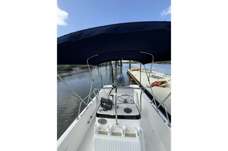 Slide: The Image of 2016 Boston Whaler 170 Montauk boat docked by a wooden pier under a blue sky. - 9