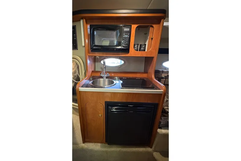 Slide: The Image of 2003 Rinker Fiesta Vee 270 kitchenette with microwave, sink, and mini-fridge. - 21