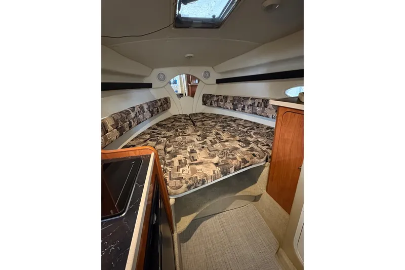 Slide: The Image of Interior cabin of 2003 Rinker Fiesta Vee 270 boat with patterned upholstery and wooden cabinetry. - 16