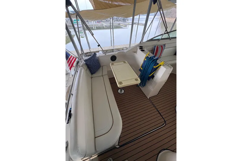 Slide: The Image of 2003 Rinker Fiesta Vee 270 boat interior with seating, table, and dock view. - 26