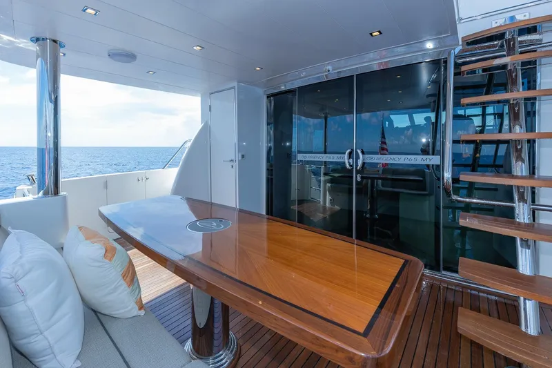 Slide: The Image of Luxurious Regency P65 yacht deck with wooden table, stairs, and ocean view, 2019 model. - 25