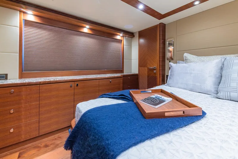 Slide: The Image of Luxurious 2019 Regency P65 yacht bedroom with elegant wood finishes and cozy bedding. - 49