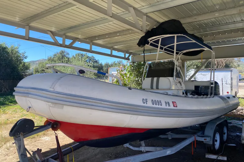Slide: The Image of Novurania 21 boat from 2000 on a trailer under a metal canopy. - 2