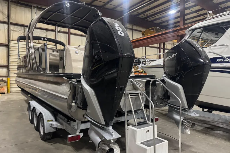 The Image of 2022 Avalon Catalina Platinum Cruise boat with dual Mercury engines in a warehouse setting. - 0