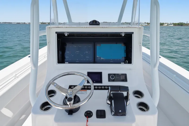 Slide: The Image of 2024 Contender 32 ST boat dashboard with steering wheel and navigation screens on open water. - 11