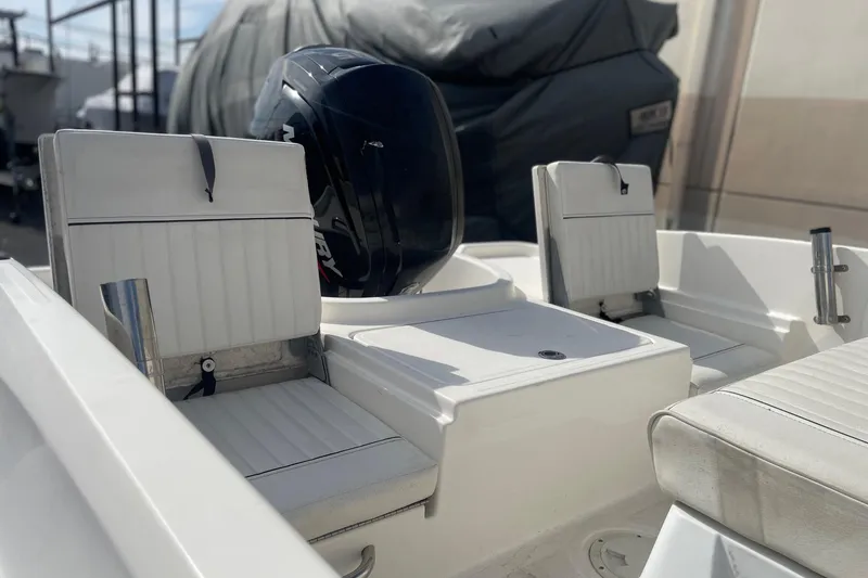 Slide: The Image of 2020 Bayliner Element F18 boat interior with white seating and motor, docked outdoors. - 7