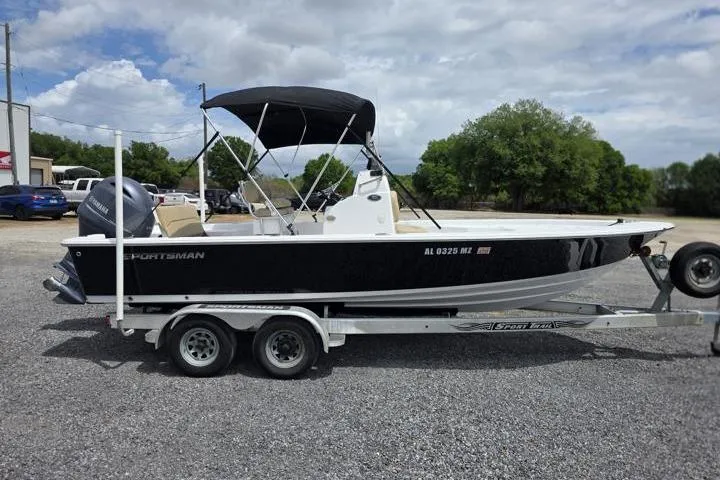 Slide: The Image of 2016 Sportmans Masters 227 Bay Boat on trailer, black hull, parked outdoors. - 6