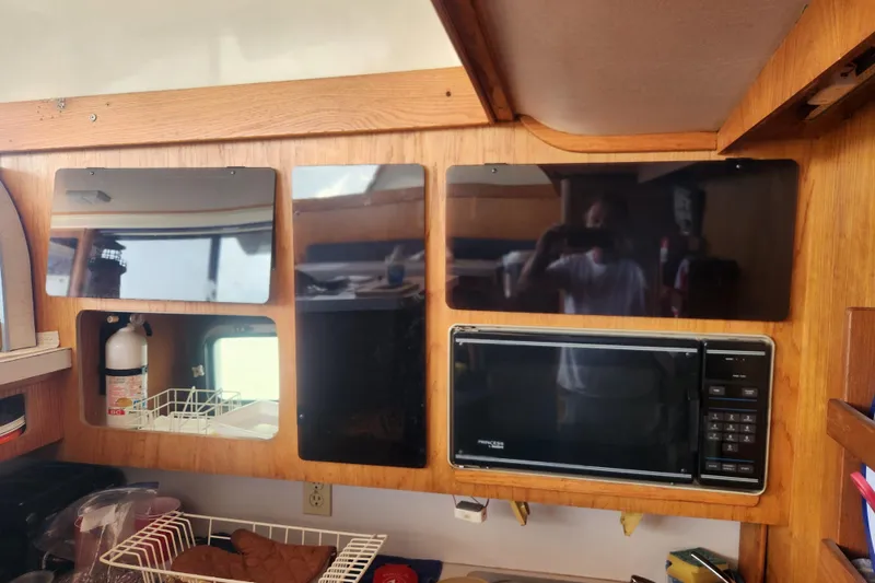 Slide: The Image of 1987 Luhrs 40 Convertible kitchen with microwave, wooden cabinets, and fire extinguisher. - 12