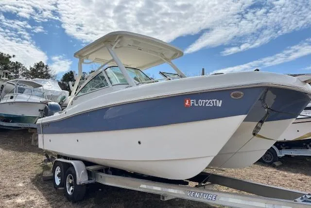 Slide: The Image of 2023 World Cat 230 DC boat on trailer under a partly cloudy sky. - 10