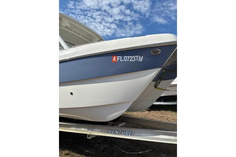 Slide: The Image of 2023 World Cat 230 DC boat on trailer under blue sky. - 13