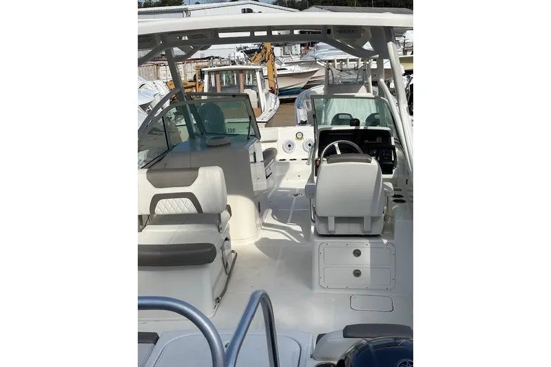 Slide: The Image of 2023 World Cat 230 DC boat interior with seating and helm, docked in a marina. - 7