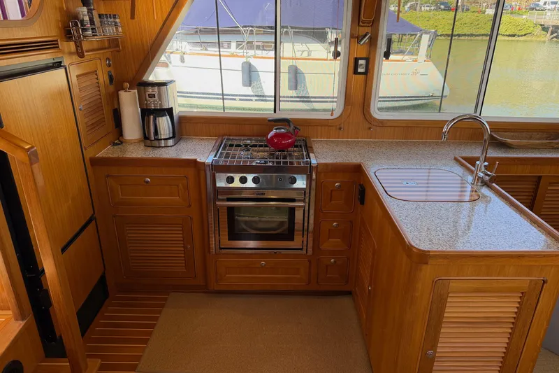 Slide: The Image of Helmsman Trawlers 38E 2020 model kitchen with stove, sink, and coffee maker. - 10