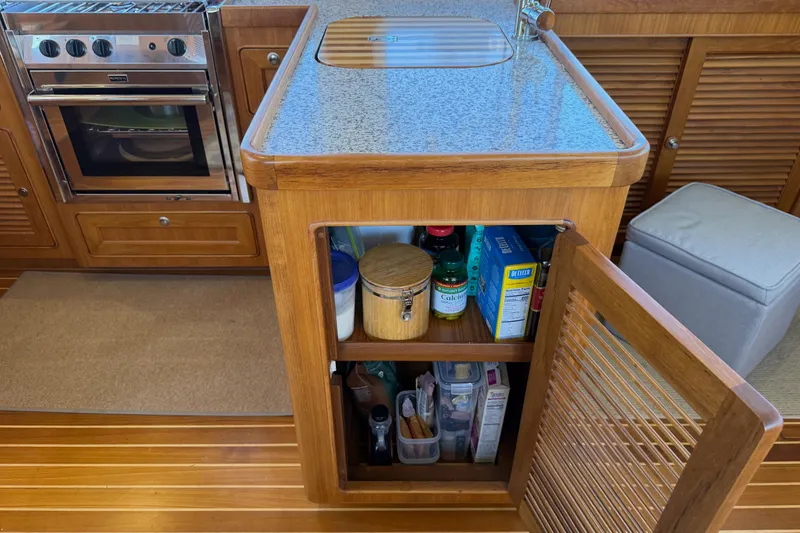 Slide: The Image of Helmsman Trawlers 38E 2020 kitchen with open cabinet, stove, and storage. - 11