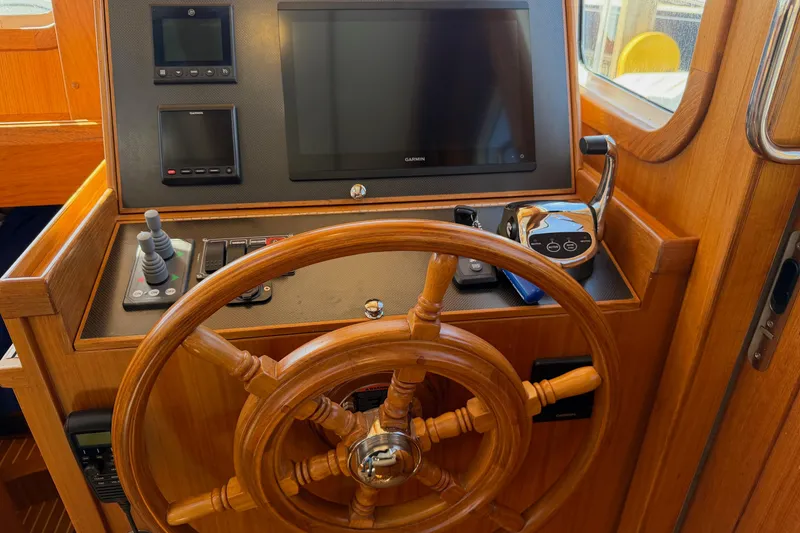 Slide: The Image of Helmsman Trawlers 38E 2020 helm station with wooden wheel and navigation controls. - 19