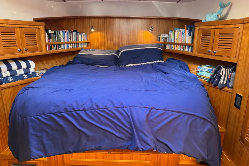 Slide: The Image of Cozy cabin bedroom in 2020 Helmsman Trawlers 38E with blue bedding and bookshelves. - 24