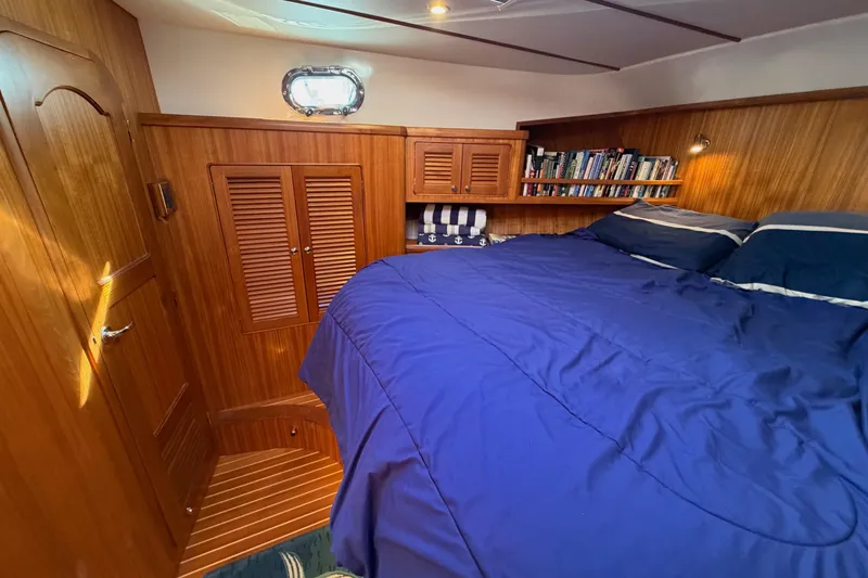 Slide: The Image of Cozy cabin interior of 2020 Helmsman Trawlers 38E with wood paneling and blue bedding. - 25
