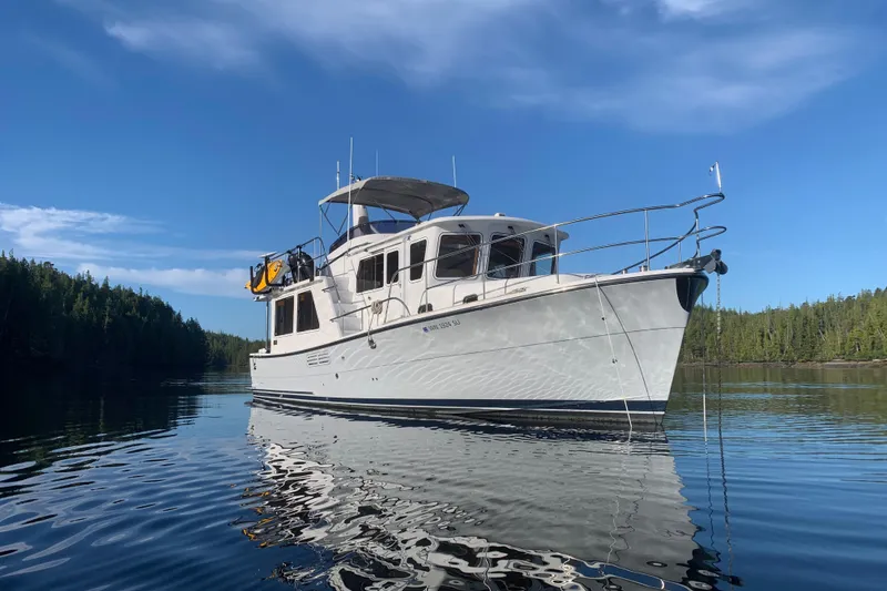 Slide: The Image of 2020 Helmsman Trawlers 38E boat on calm water, surrounded by forested landscape. - 48