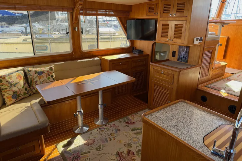 Slide: The Image of Interior of 2020 Helmsman Trawlers 38E, featuring wood finishes and cozy seating area. - 5