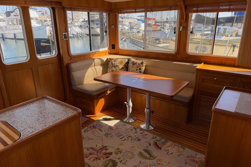 Slide: The Image of Interior of 2020 Helmsman Trawlers 38E, featuring a cozy dining area with marina views. - 6