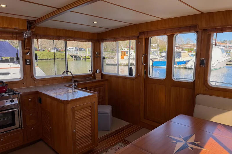 Slide: The Image of Interior of 2020 Helmsman Trawlers 38E, featuring wood finish and marina view. - 7