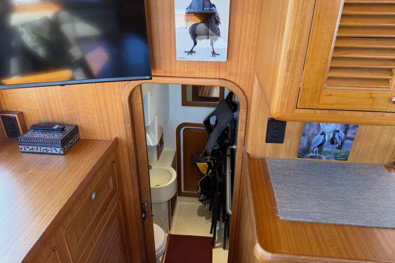 Slide: The Image of Interior of 2020 Helmsman Trawlers 38E, featuring wooden cabinetry and compact bathroom. - 9