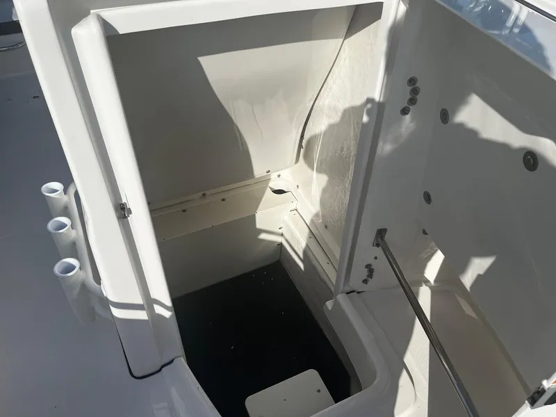 Slide: The Image of 2025 Robalo R180 Center Console storage compartment with open hatch and rod holders. - 15