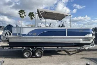 The Image of 2023 Suntracker G3 Select 322 CC pontoon boat on trailer, under blue sky. - 1