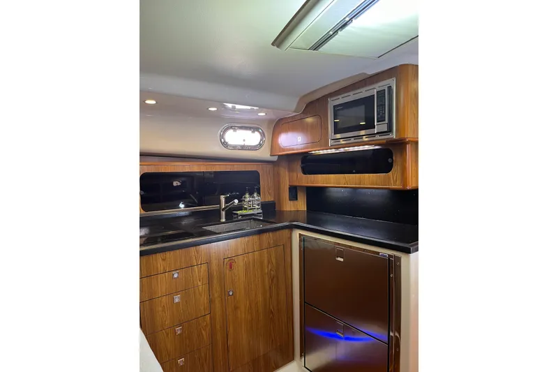 Slide: The Image of 2009 Pursuit OS 375 Offshore yacht kitchen with wood cabinetry and modern appliances. - 25
