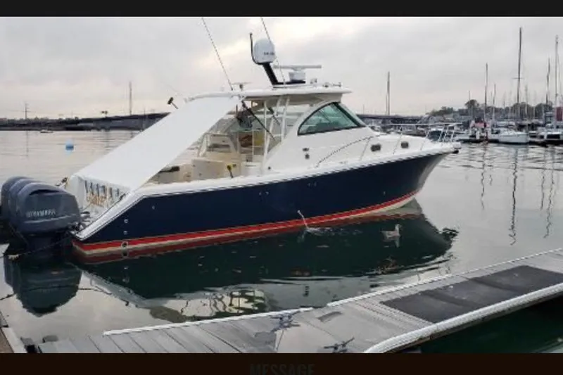 Slide: The Image of 2009 Pursuit OS 375 Offshore boat docked in a marina, featuring twin outboard engines. - 3