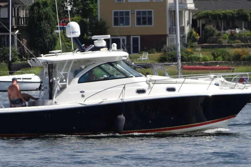 Slide: The Image of 2009 Pursuit OS 375 Offshore boat cruising near waterfront homes. - 4